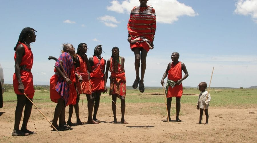 Photo by Randy Fath person in red dress jumping over brown soil