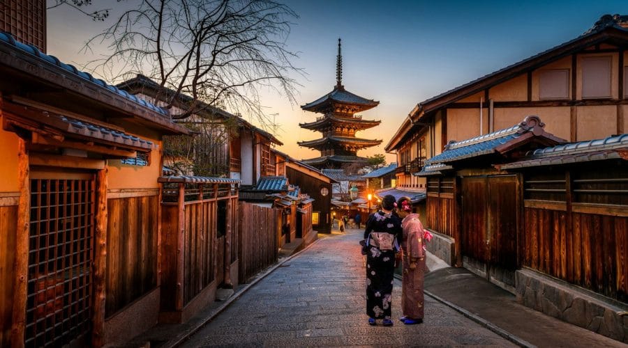 Photo by Sorasak two women in purple and pink kimono standing on street